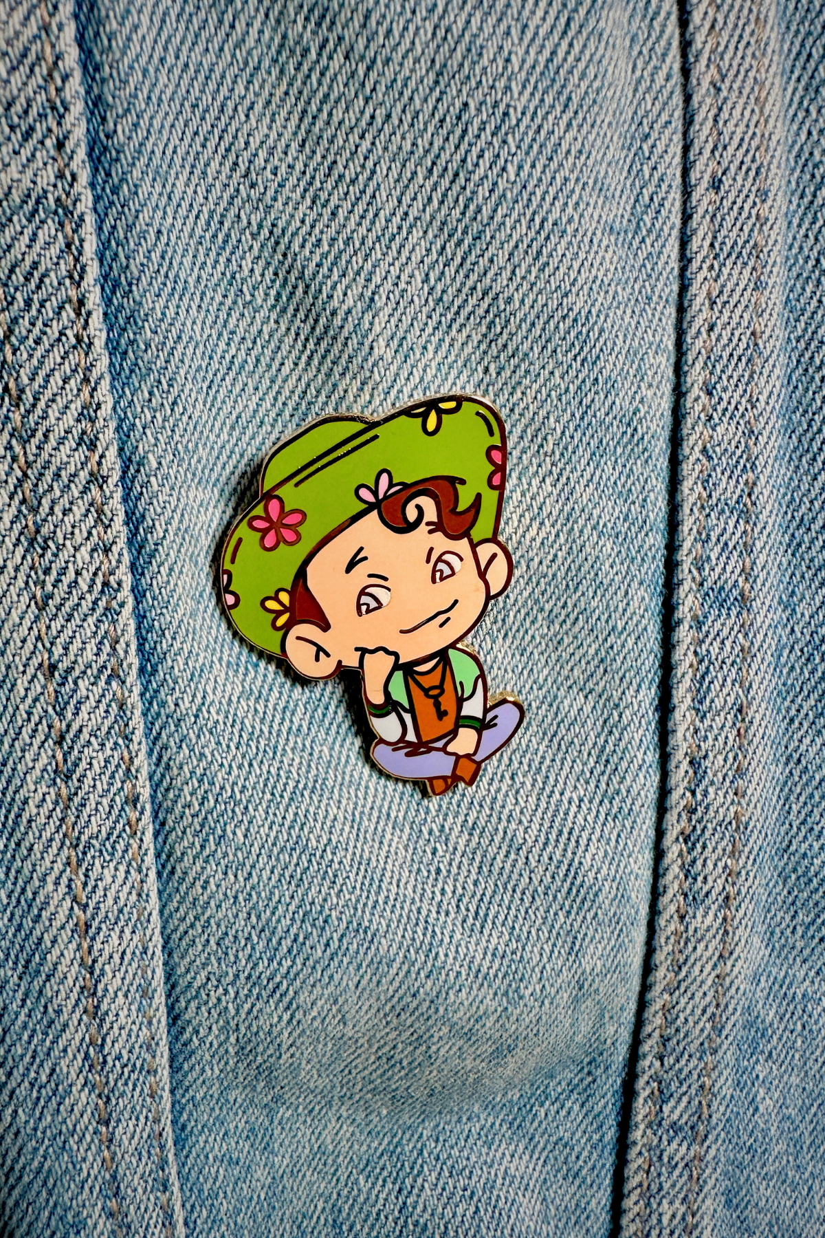 The Scott Postcards enamel pin prominently featured on a denim jacket