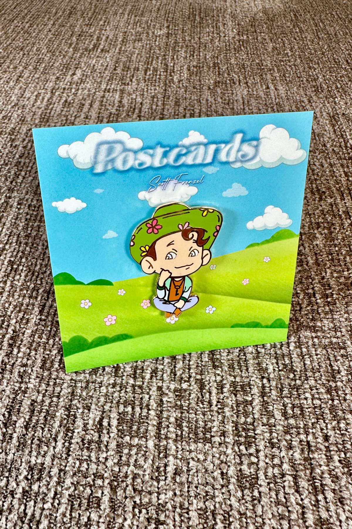 the Postcards pin featured on an upholstered backdrop